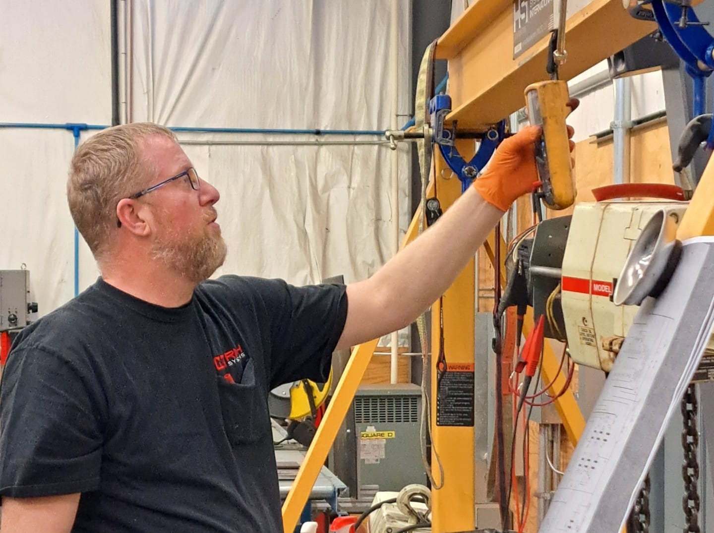 Industrial crane technician rebuilding electric wire rope hoist assembly