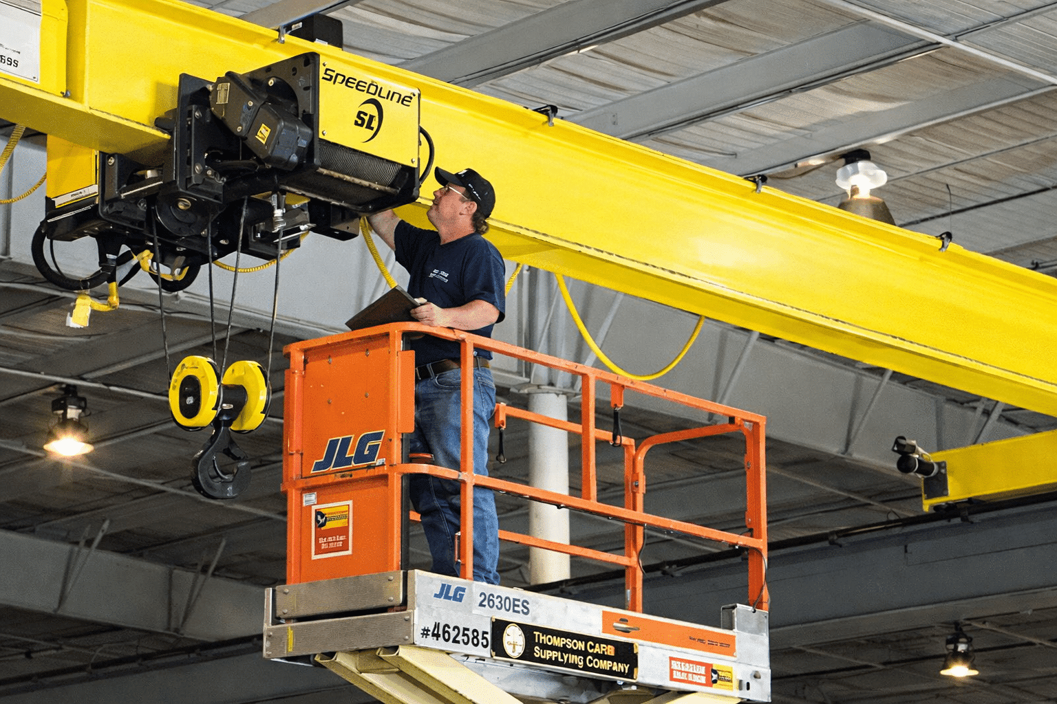 Certified crane technician conducting structural and electrical inspection on overhead bridge crane